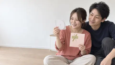 ギフトラッピングからケースを取り出して笑う 2 人